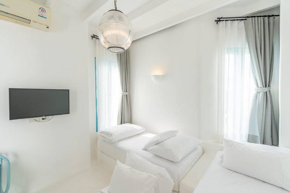 Une chambre d’hôtel avec un lit, un téléviseur à écran plat et une fenêtre avec des rideaux.