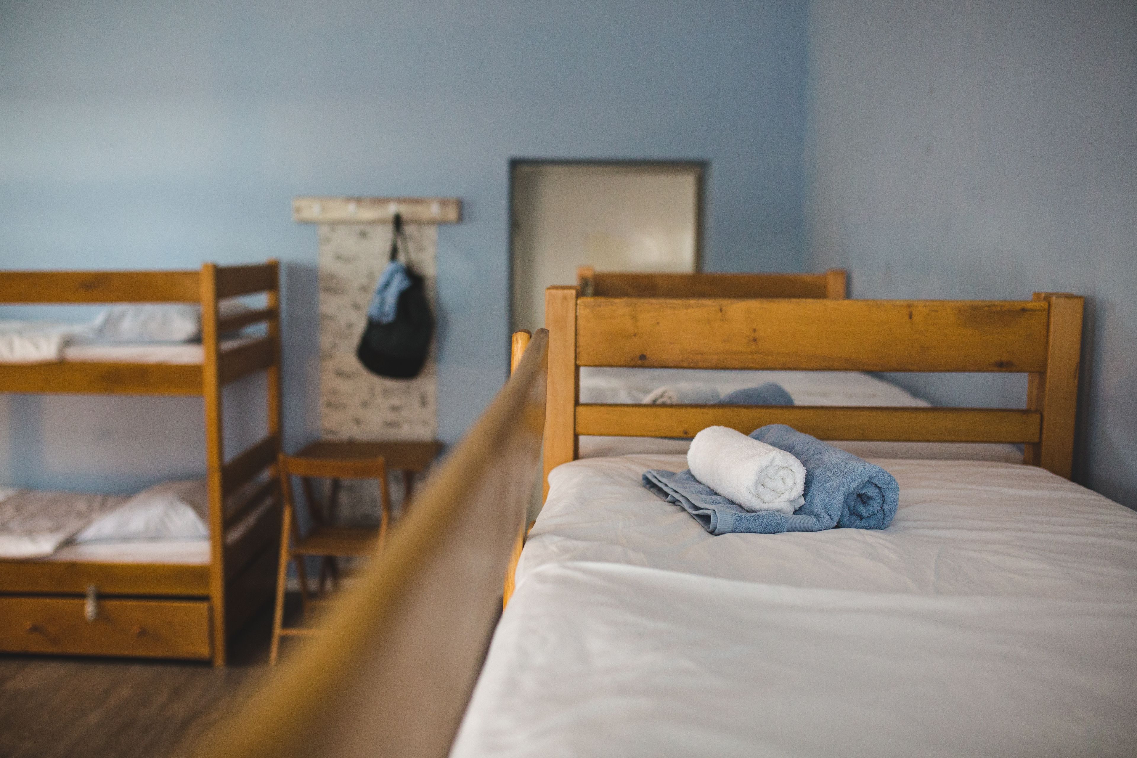 A bunk bed room with a wooden headboard, a small table with a bag, and a framed picture on the wall.
