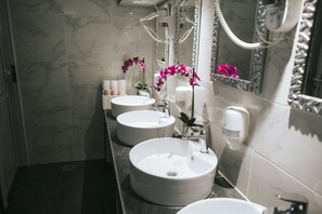 Une salle de bain moderne avec trois vasques rondes, un sèche-cheveux et un miroir doté d’un cadre décoratif.