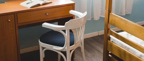 Una habitación con un escritorio de madera, una silla blanca con cojín azul y una cama nido de madera.