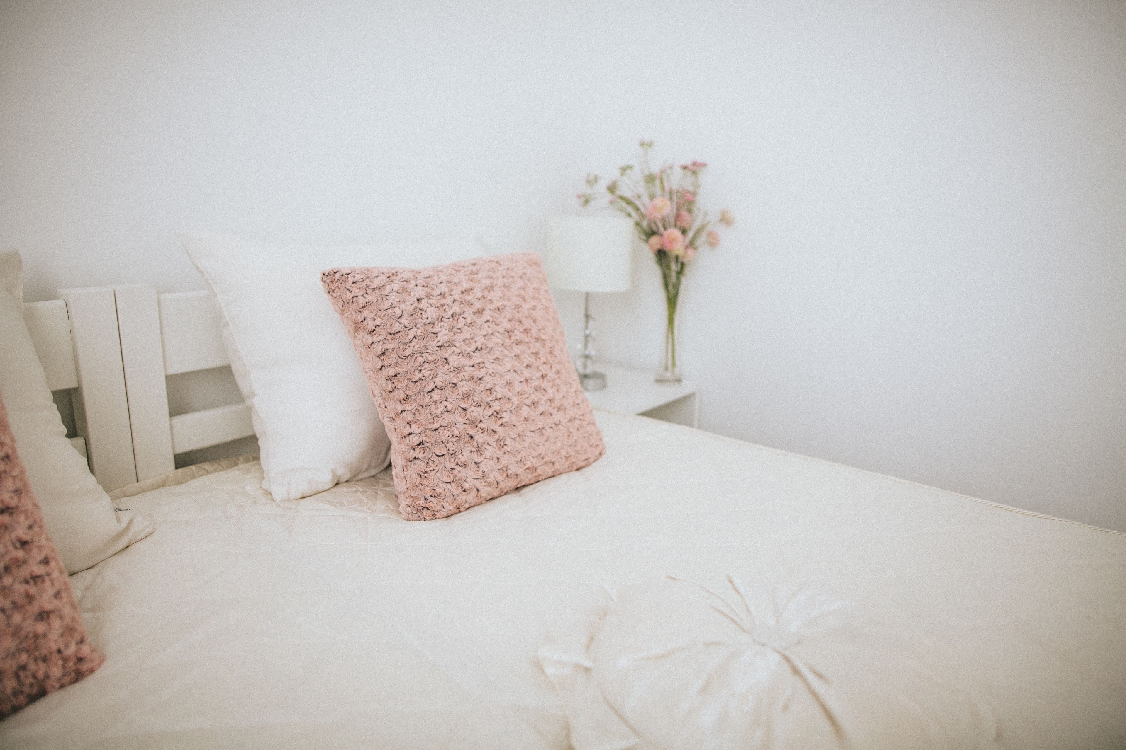 Un llit ben arropat amb roba de llit blanca i una almoçada amb motius florals rosades.