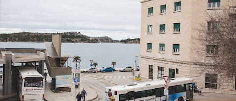 A bus station with a bus, cars, and pedestrians.