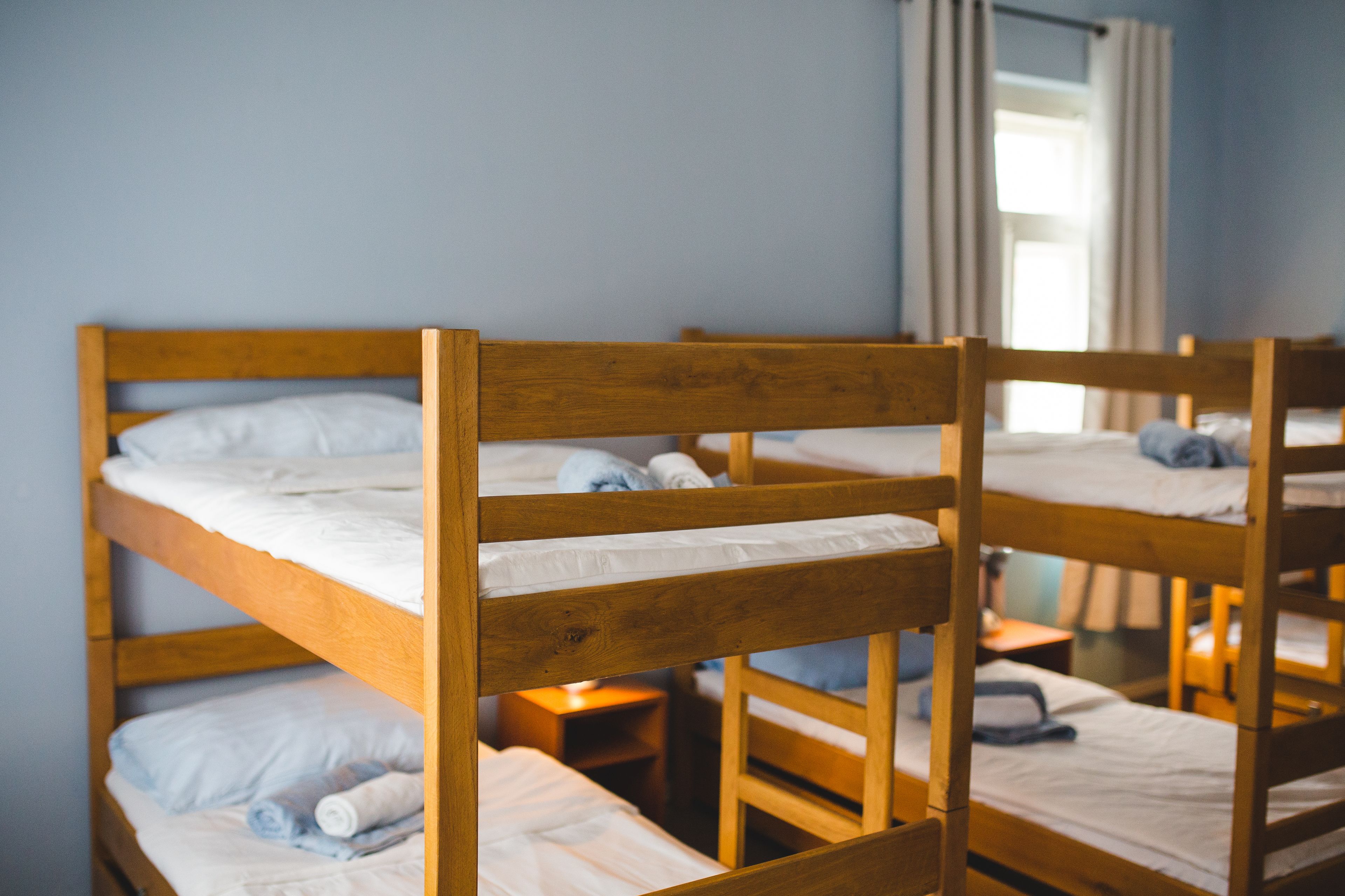 A bunk bed room with wooden frames and white bedding.