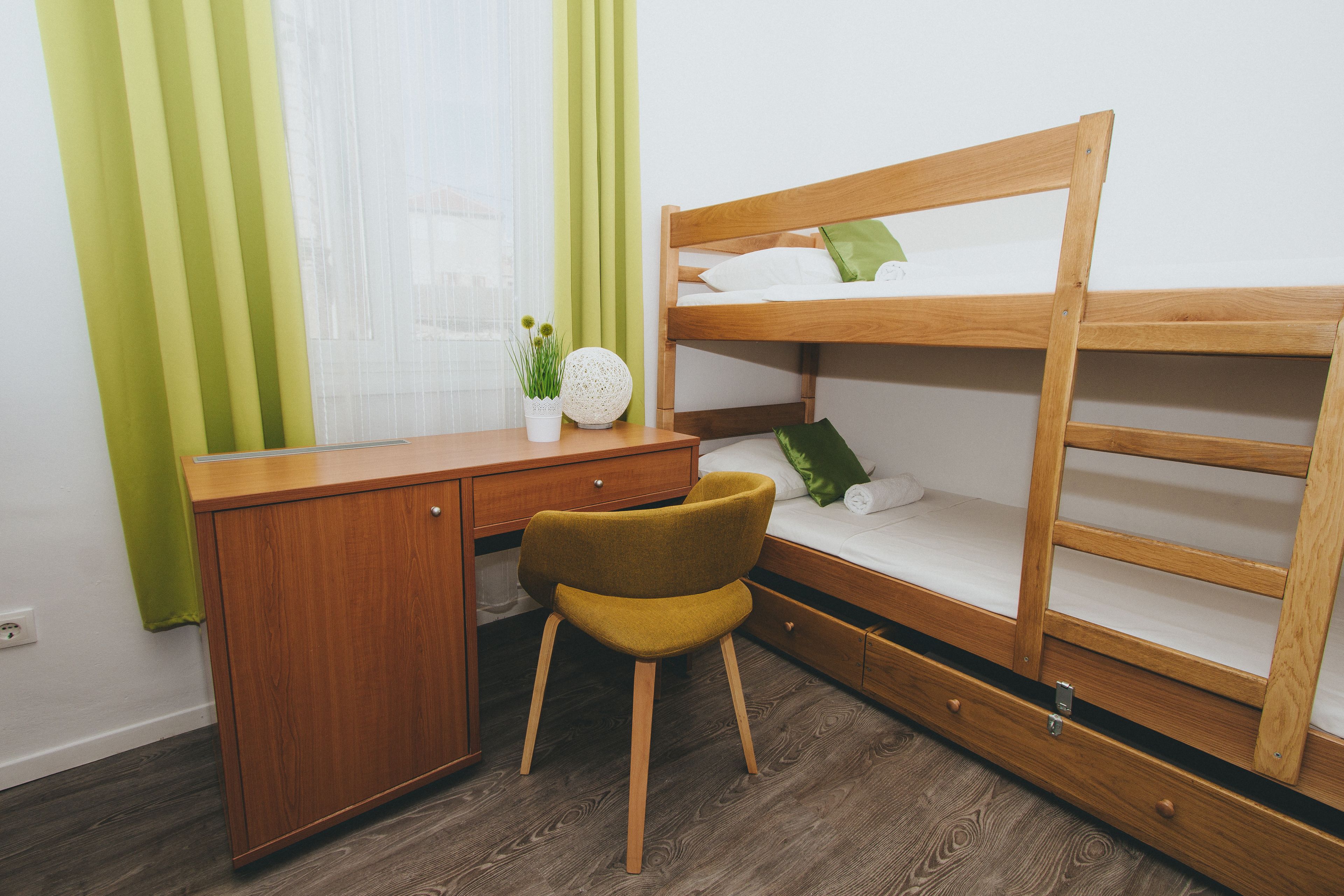 A bunk bed with a wooden frame, a desk with a drawer, a chair, and a potted plant.