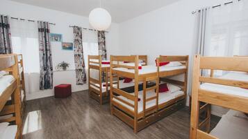 Quarto com beliches, um banquinho vermelho e luminária pendente.