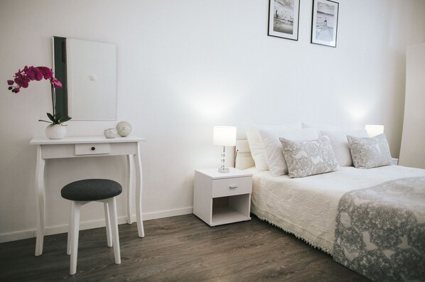Une chambre à coucher comprenant un lit, une table de chevet, une commode et un petit bureau avec une chaise.