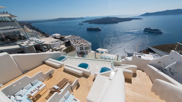 A rooftop terrace with outdoor seating, a pool, and a view of the sea and islands. - On the Cliff (Santorini)