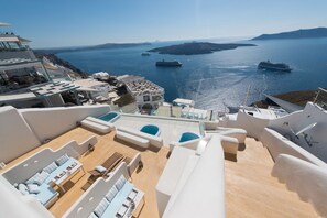 A rooftop terrace with outdoor seating, a pool, and a view of the sea and islands. - On the Cliff (Santorini)