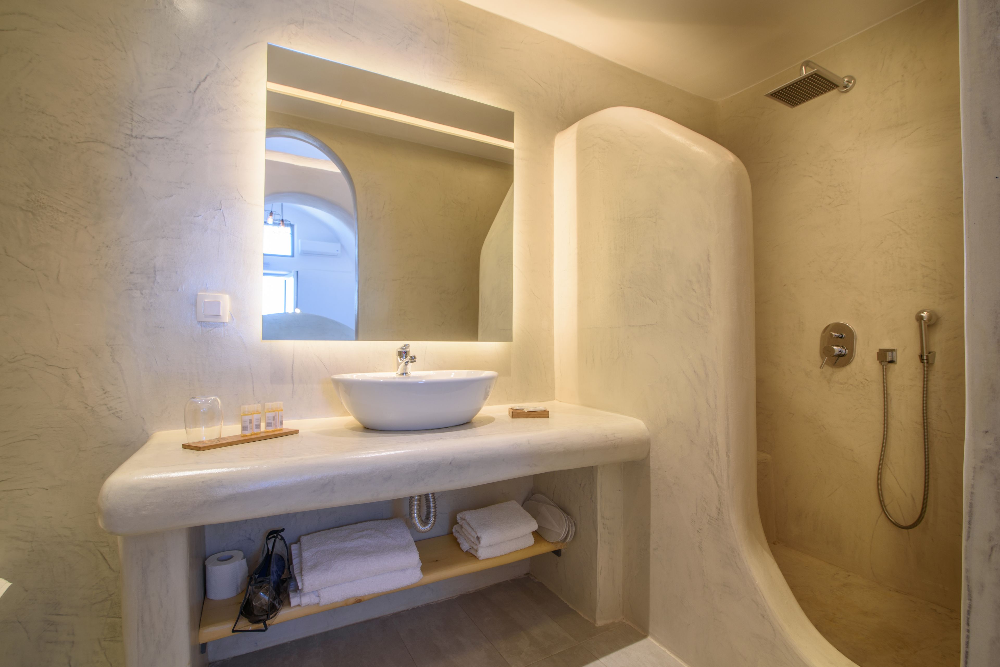 A bathroom with a white sink, a mirror, a shower, and a towel rack.