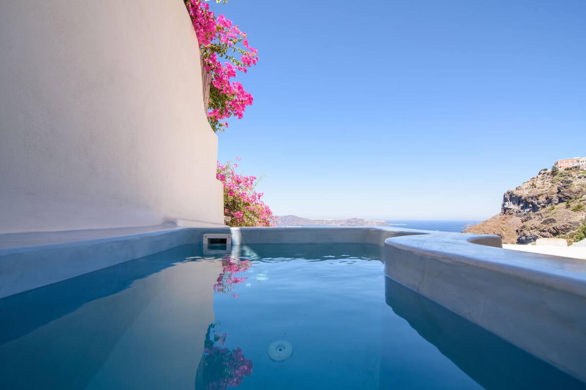 Une piscine d’eau cristalline, d’un bleu éclatant, avec vue sur la mer et un paysage rocheux.