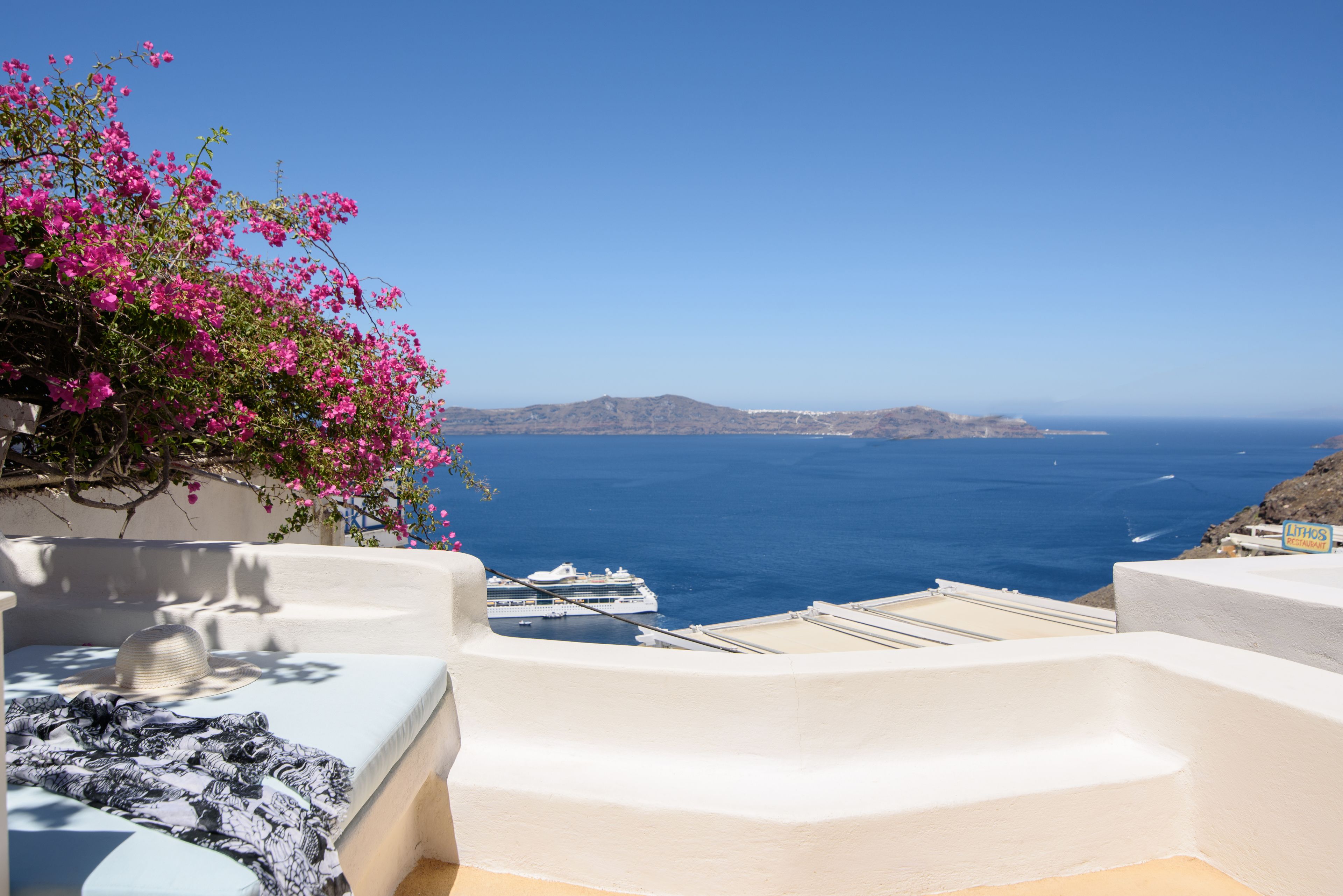 A white-walled room with a view of the sea and boats.