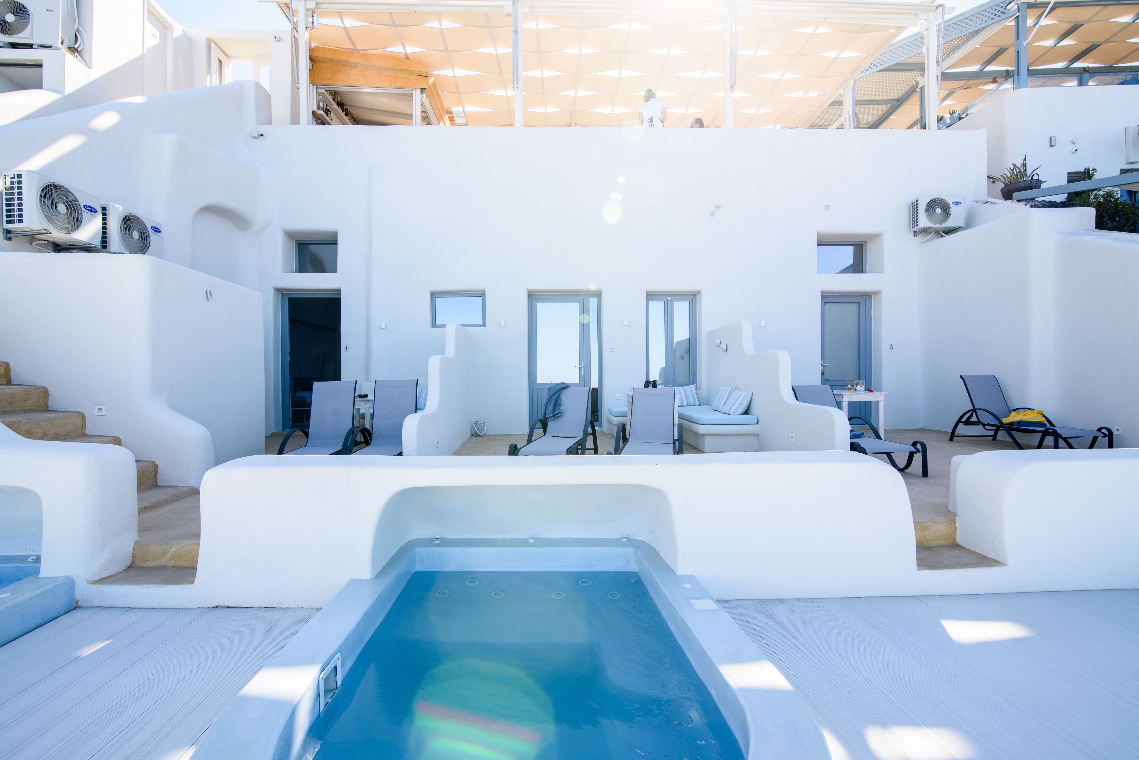 A modern, white interior with a swimming pool, seating areas, and a staircase leading to an upper level.