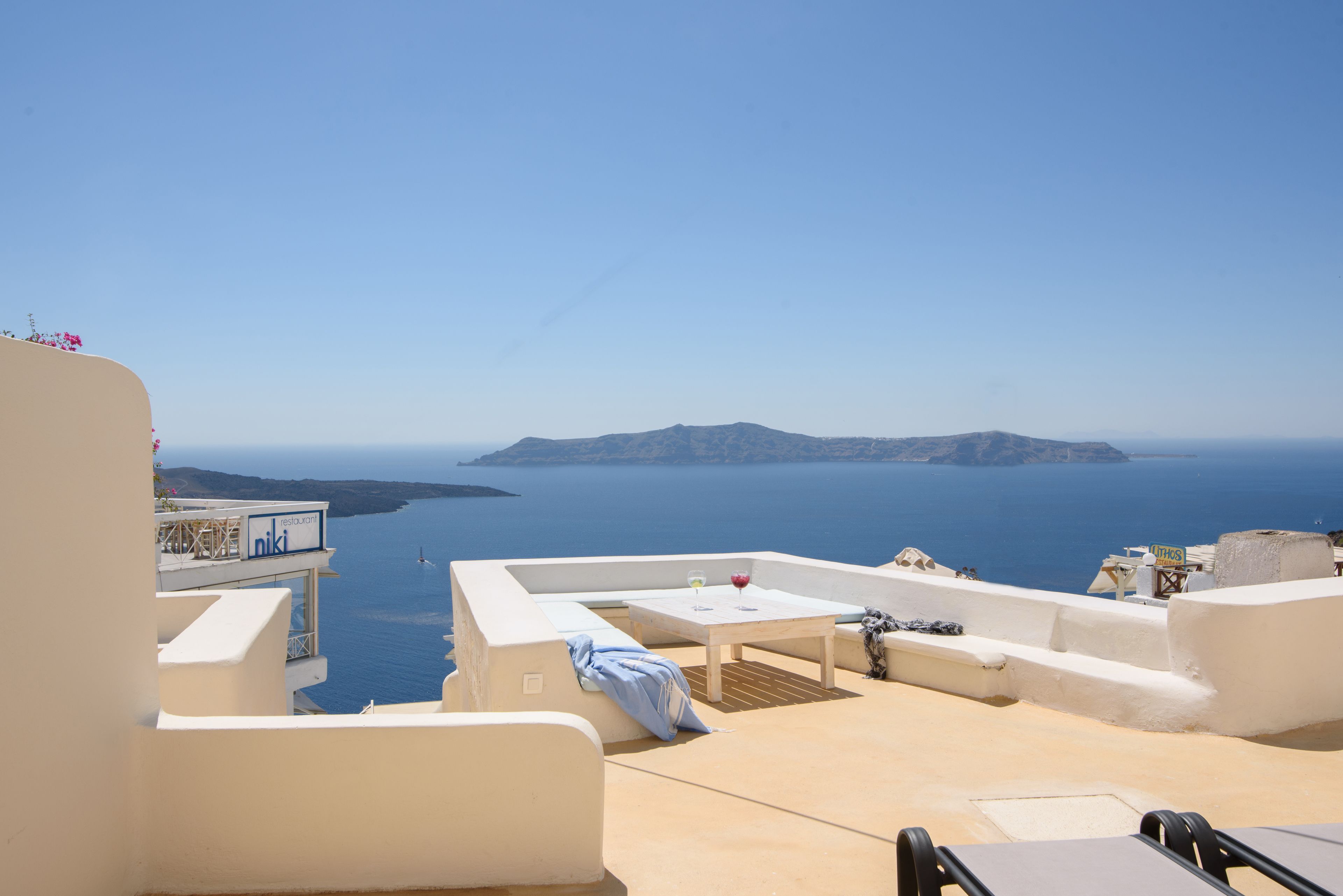 Une terrasse avec une table et des chaises donnant sur la mer.