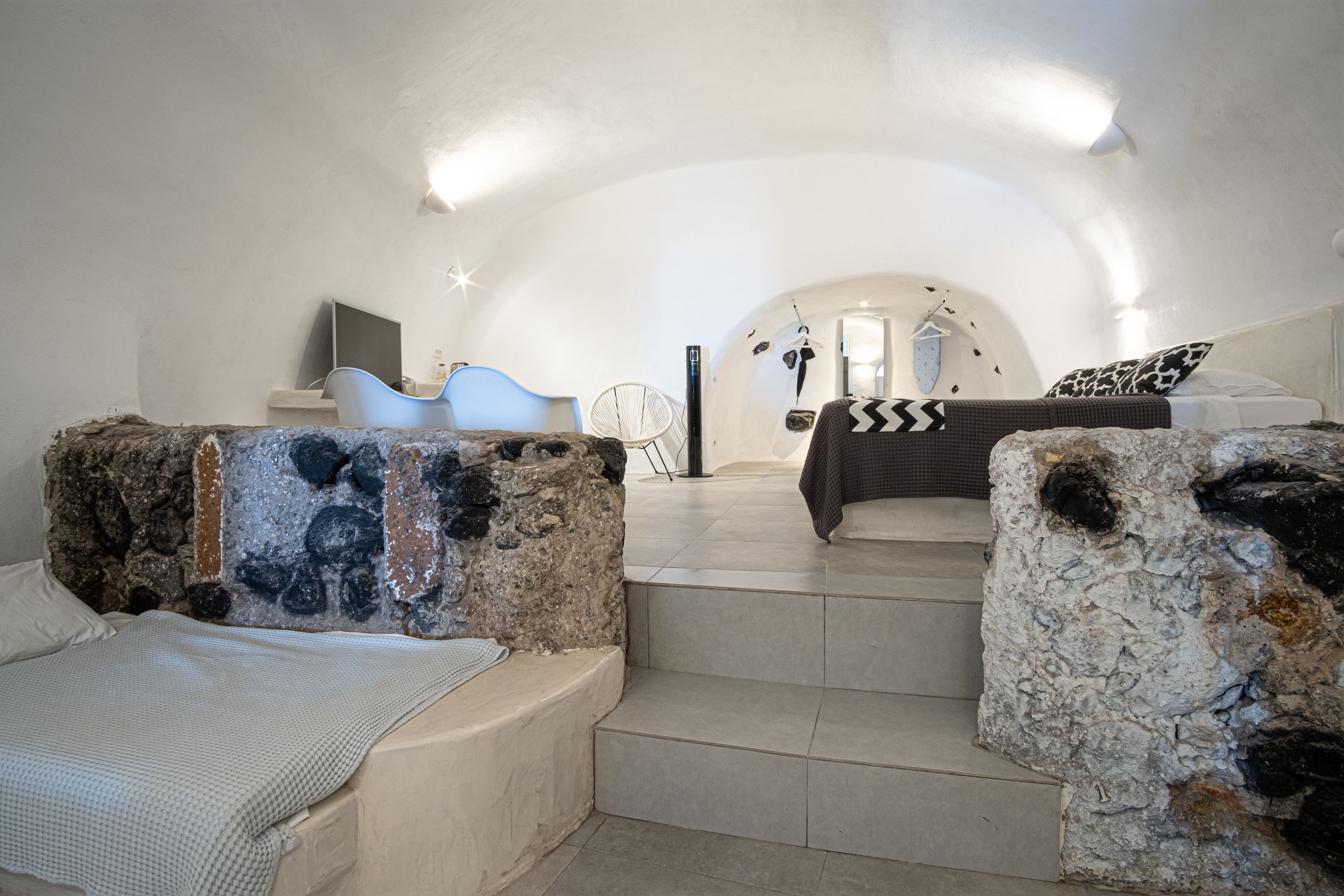 Een knus slaapkamer met een stenen muur, een bed met een beddegoed met een patroon, en een stoel.