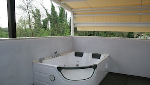 Bagno angolare con vasca freestanding, una finestra e vista sugli alberi.