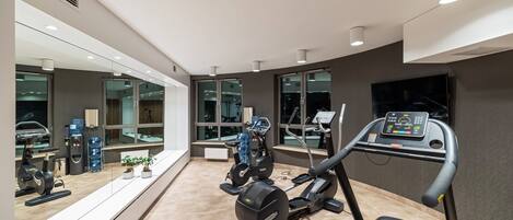 A modern gym with a treadmill, elliptical, and stationary bikes.