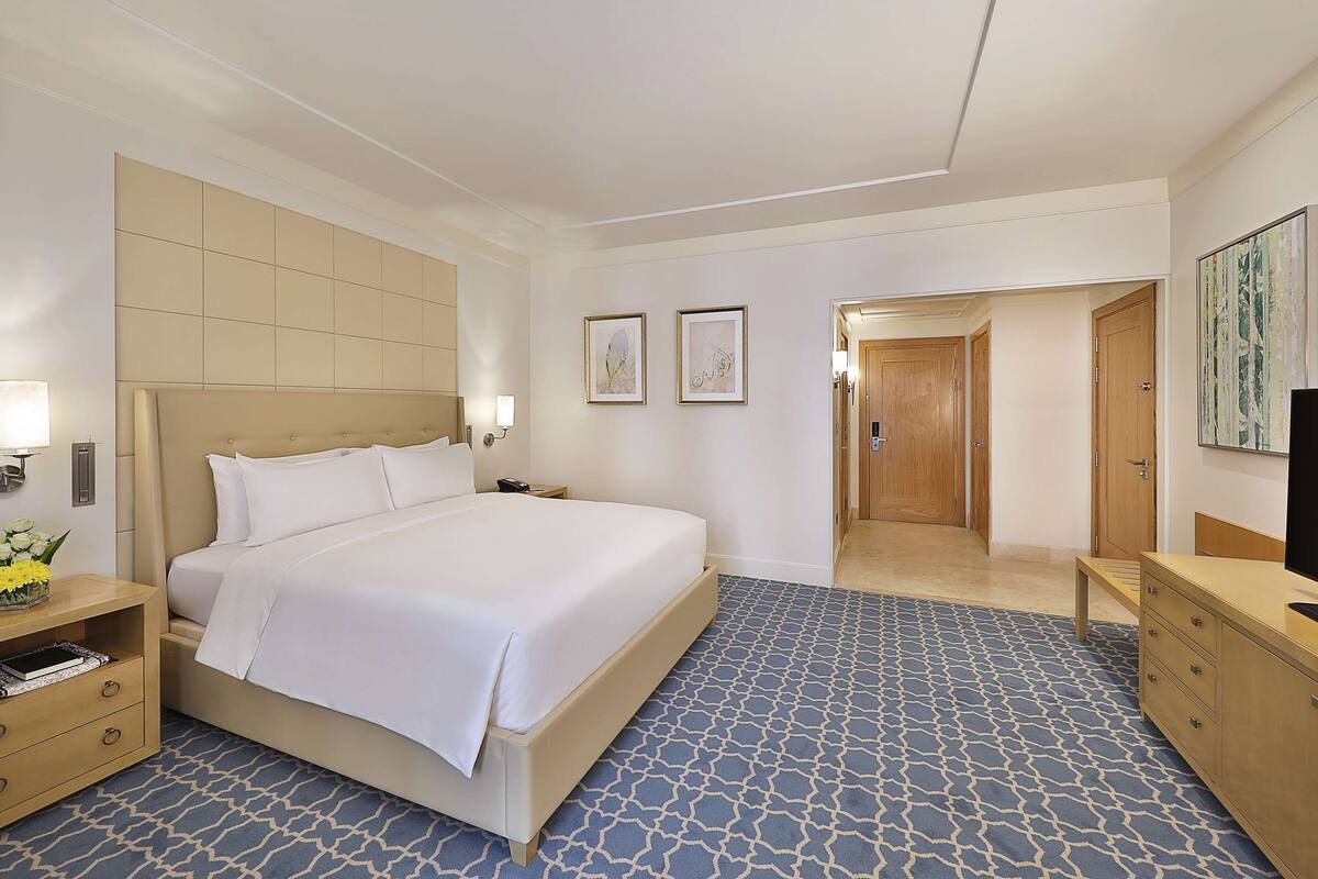 A hotel room with a large bed, bedside tables, a wardrobe, and a television.