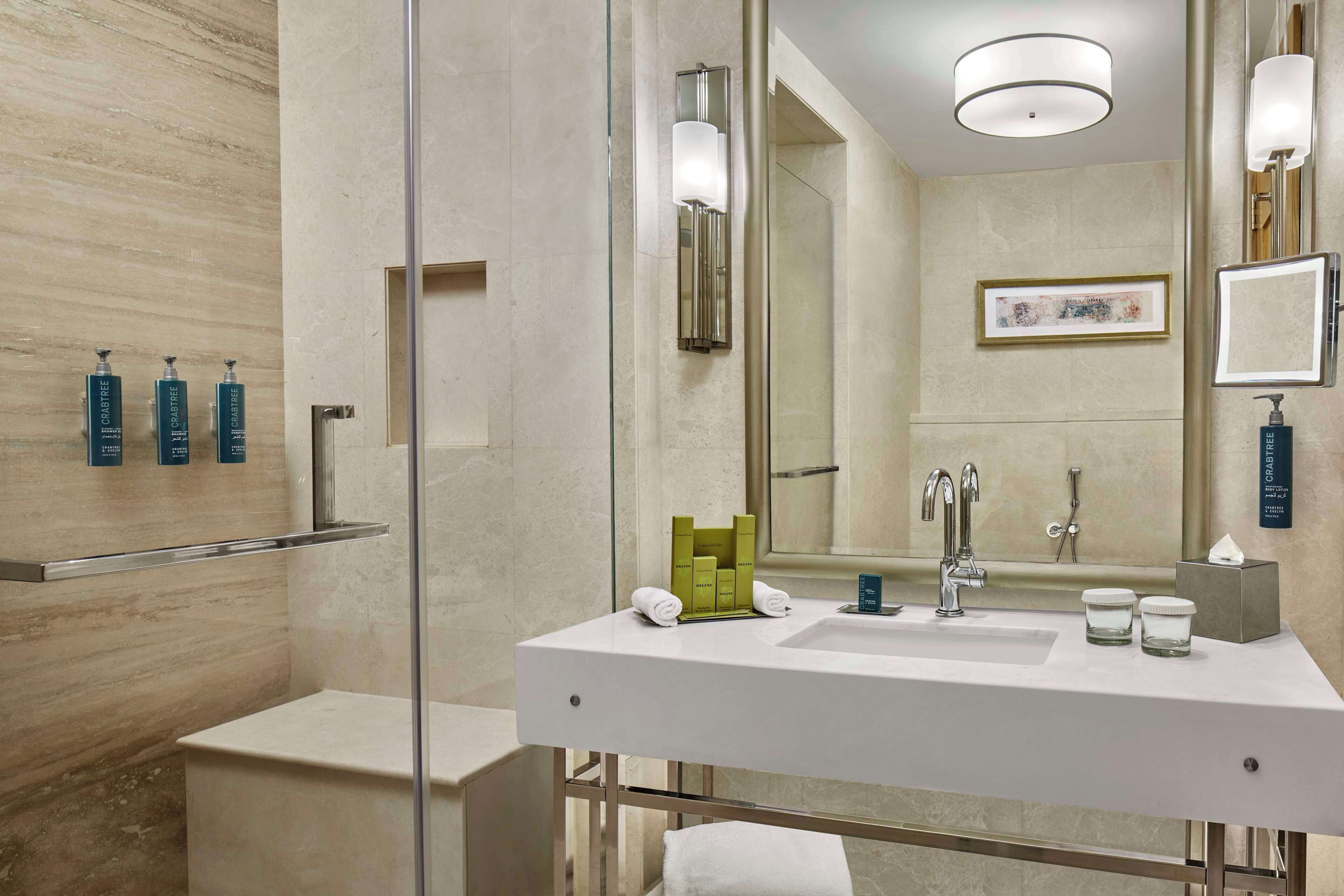 A modern bathroom with a white sink, glass shower enclosure, and a large mirror.