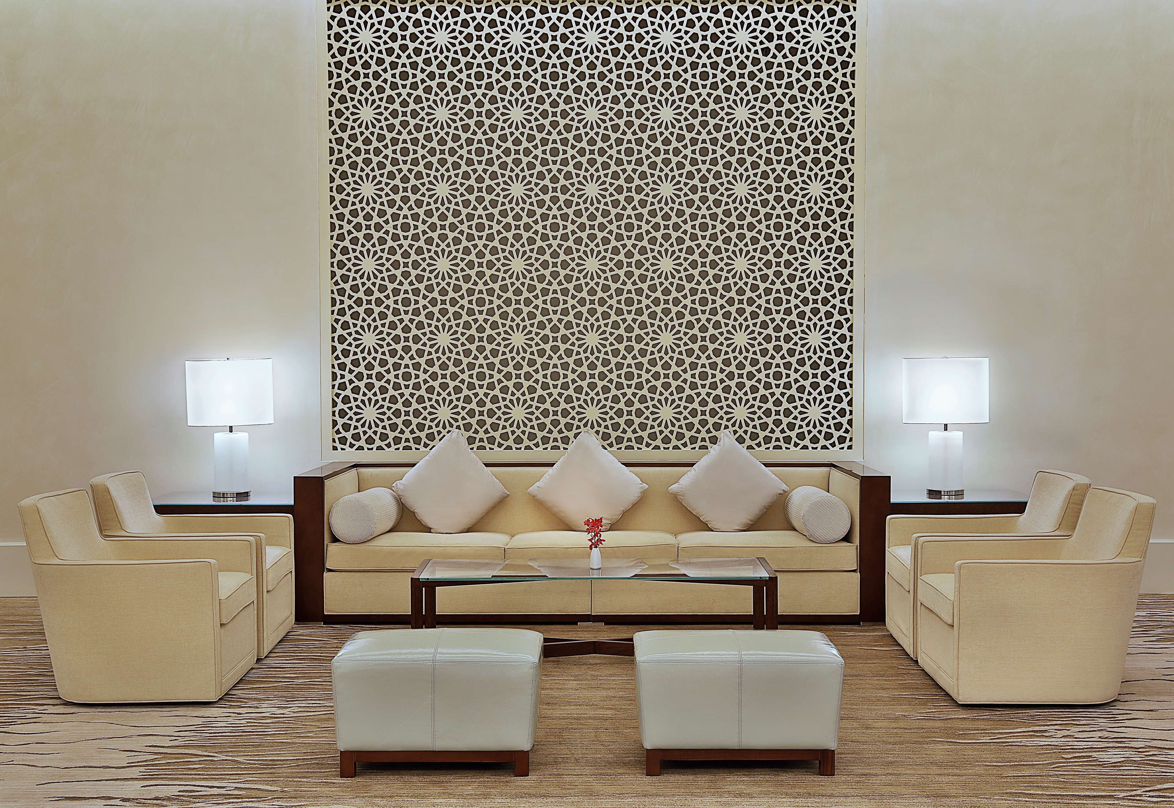 Un salon moderne comprenant un canapé, deux fauteuils, une table basse et un panneau décoratif mural.