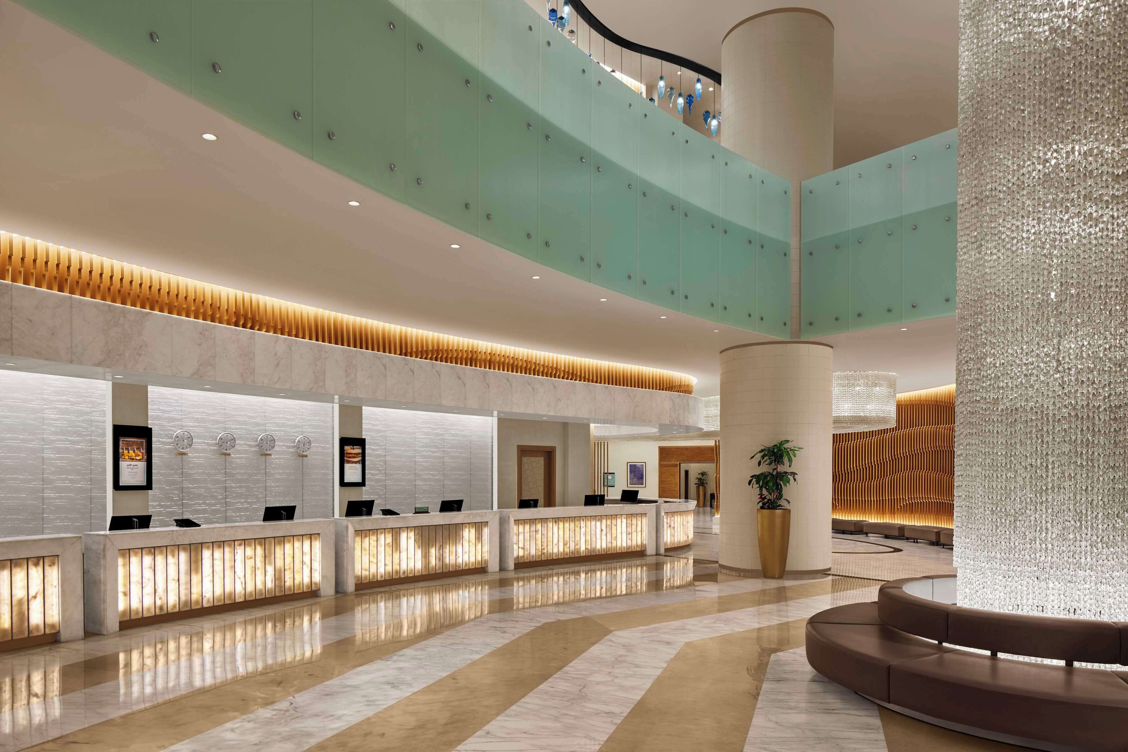 A spacious lobby with a reception desk, a staircase, and a decorative column.