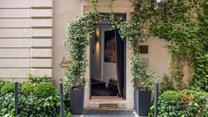 A hotel entrance with a covered entrance, a stone wall, and a potted plant. - Hotel Vilòn (Rome)