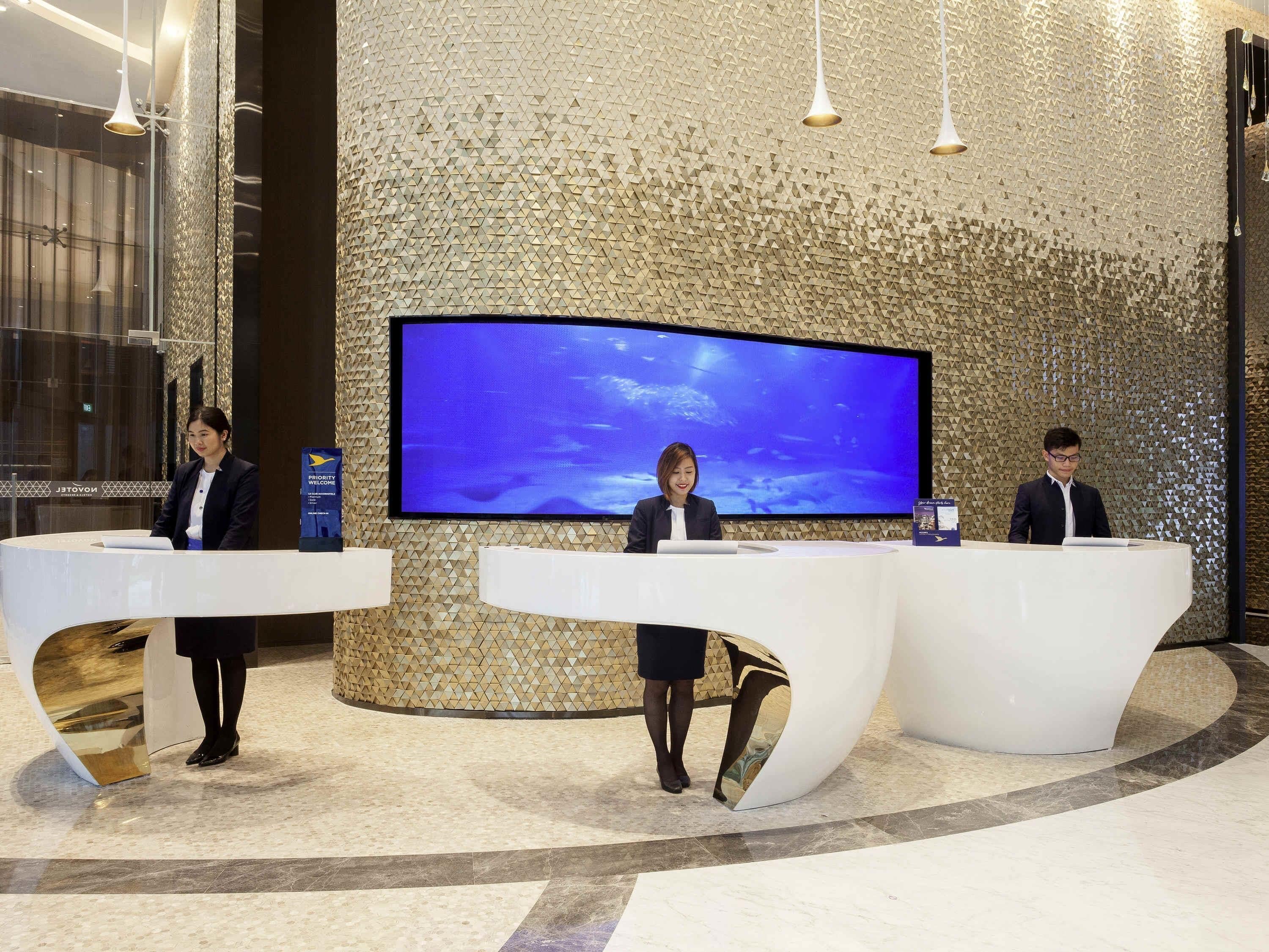 A reception area with three receptionists, a large flat-screen TV, and a textured wall.