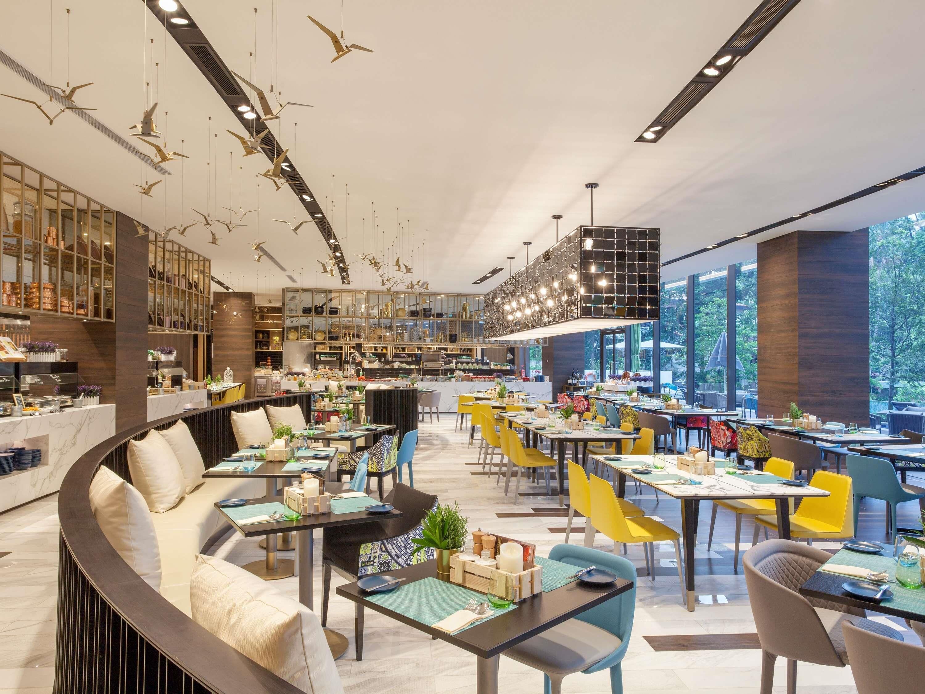 A modern restaurant with a curved seating area, multiple dining tables, and a central bar.
