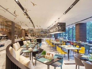 Un restaurante moderno con una zona de estar curva, varias mesas de comedor y una barra central.