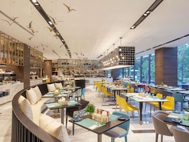 Un restaurante moderno con una zona de estar curva, varias mesas de comedor y una barra central.