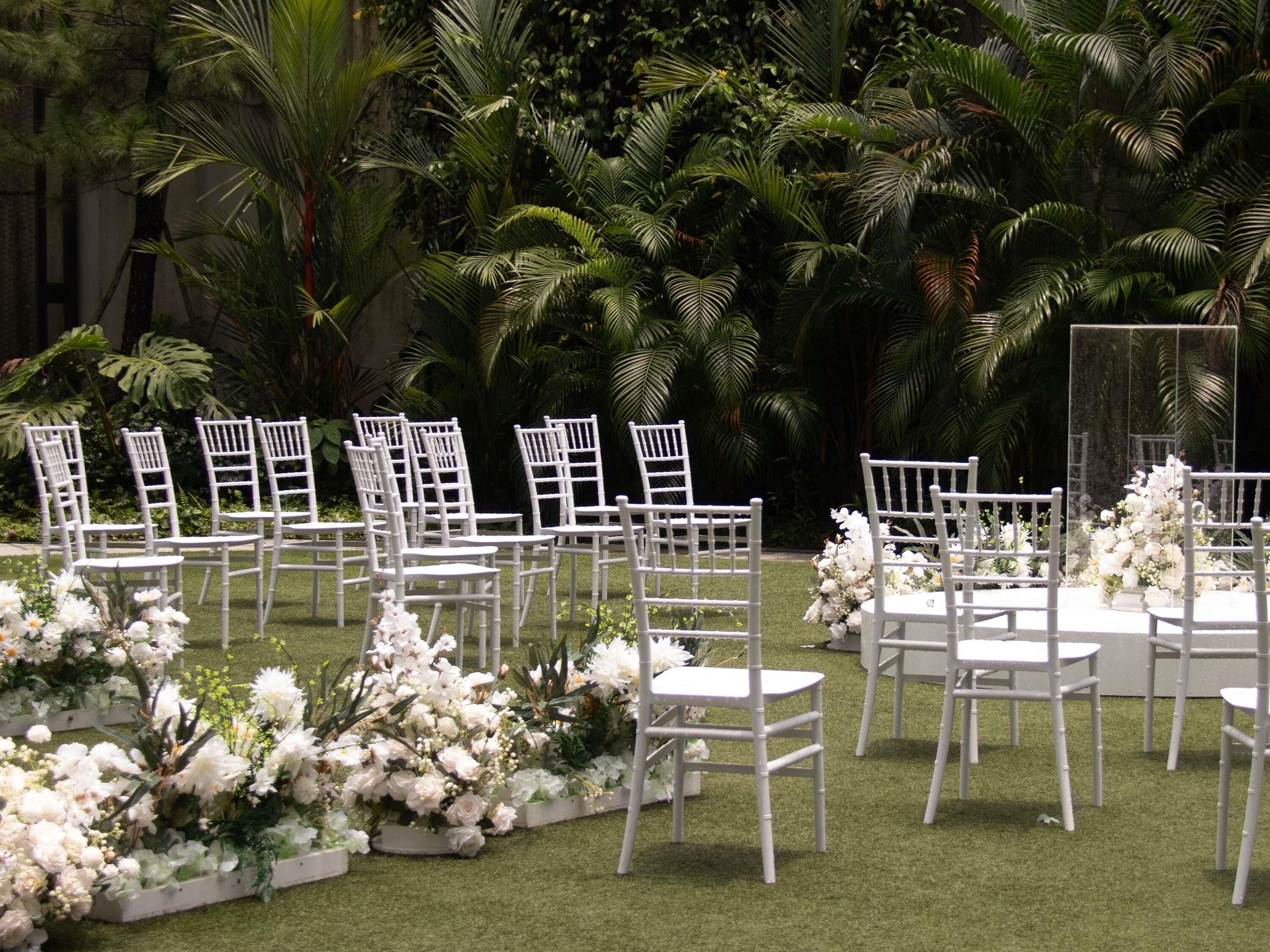Ein Außenbereich für Veranstaltungen mit Reihen weißer Stühle und Blumenarrangements.