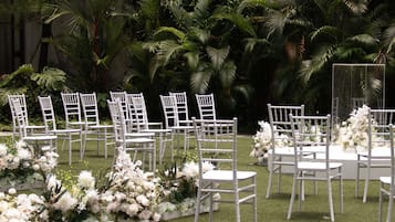 Ein Außenbereich für Veranstaltungen mit Reihen weißer Stühle und Blumenarrangements.