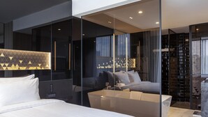Una habitación de hotel moderna con una cama grande, un área de descanso y un separador de vidrio.