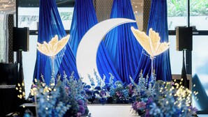 Un escenario con cortinas azules, una luna creciente y luces decorativas.