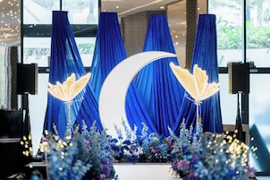 A stage with blue curtains, a crescent moon, and decorative lights.