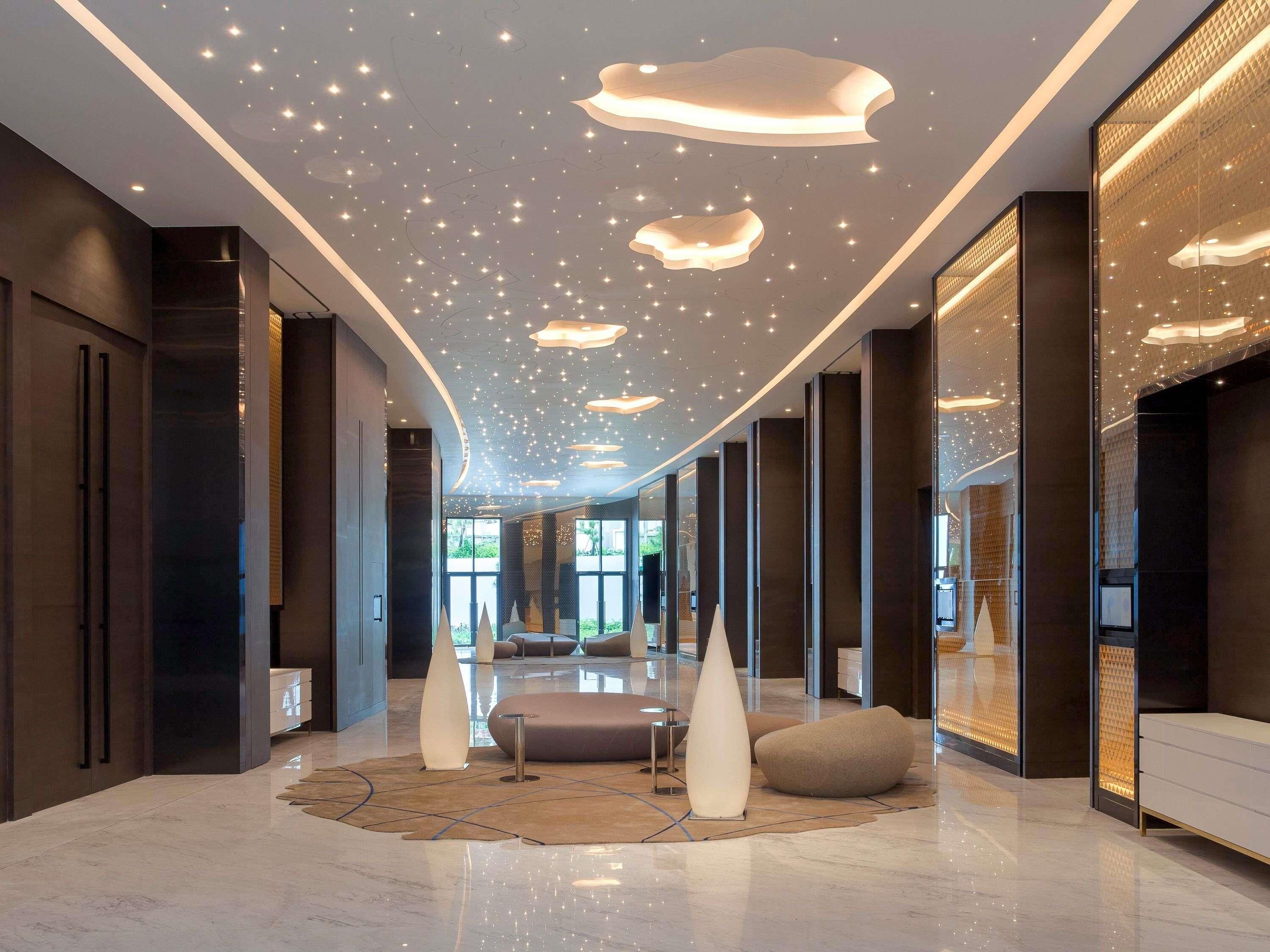 A modern lobby with a curved ceiling, recessed lighting, and a central seating area with a patterned rug.