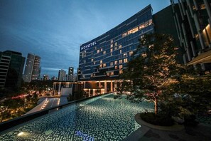 Een Novotel hotel met een modern design, met een dakzwembad met verlichte tegels.