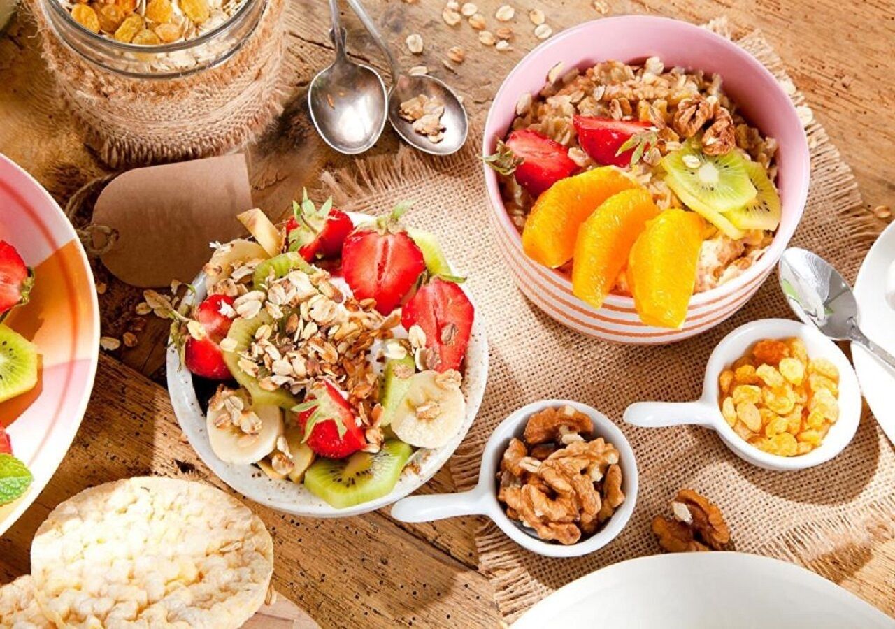 A breakfast setting with bowls of cereal, fruits, and granola.