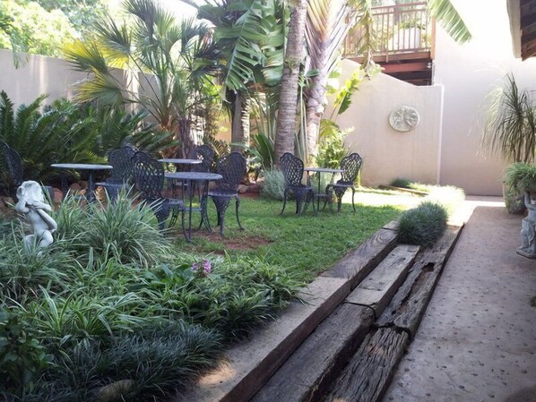 A patio area with outdoor seating, surrounded by lush greenery and palm trees.