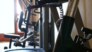 A stationary bike and treadmill in a gym with a door and window in the background.