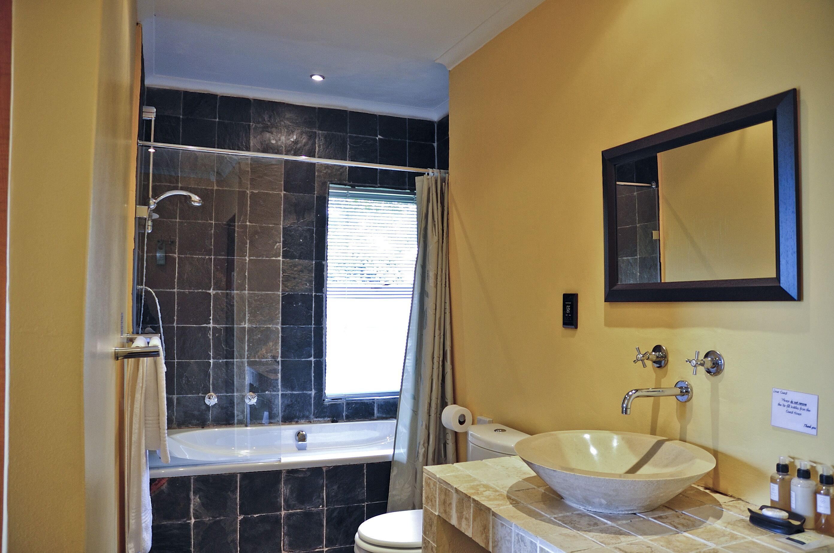 A bathroom with a bathtub, toilet, sink, and a large mirror.