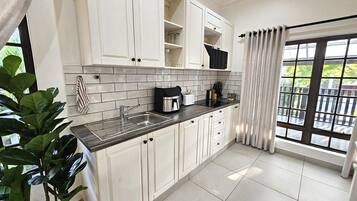 A modern kitchen with white cabinets, a black countertop, and a sink. There is a window with a view of greenery outside.