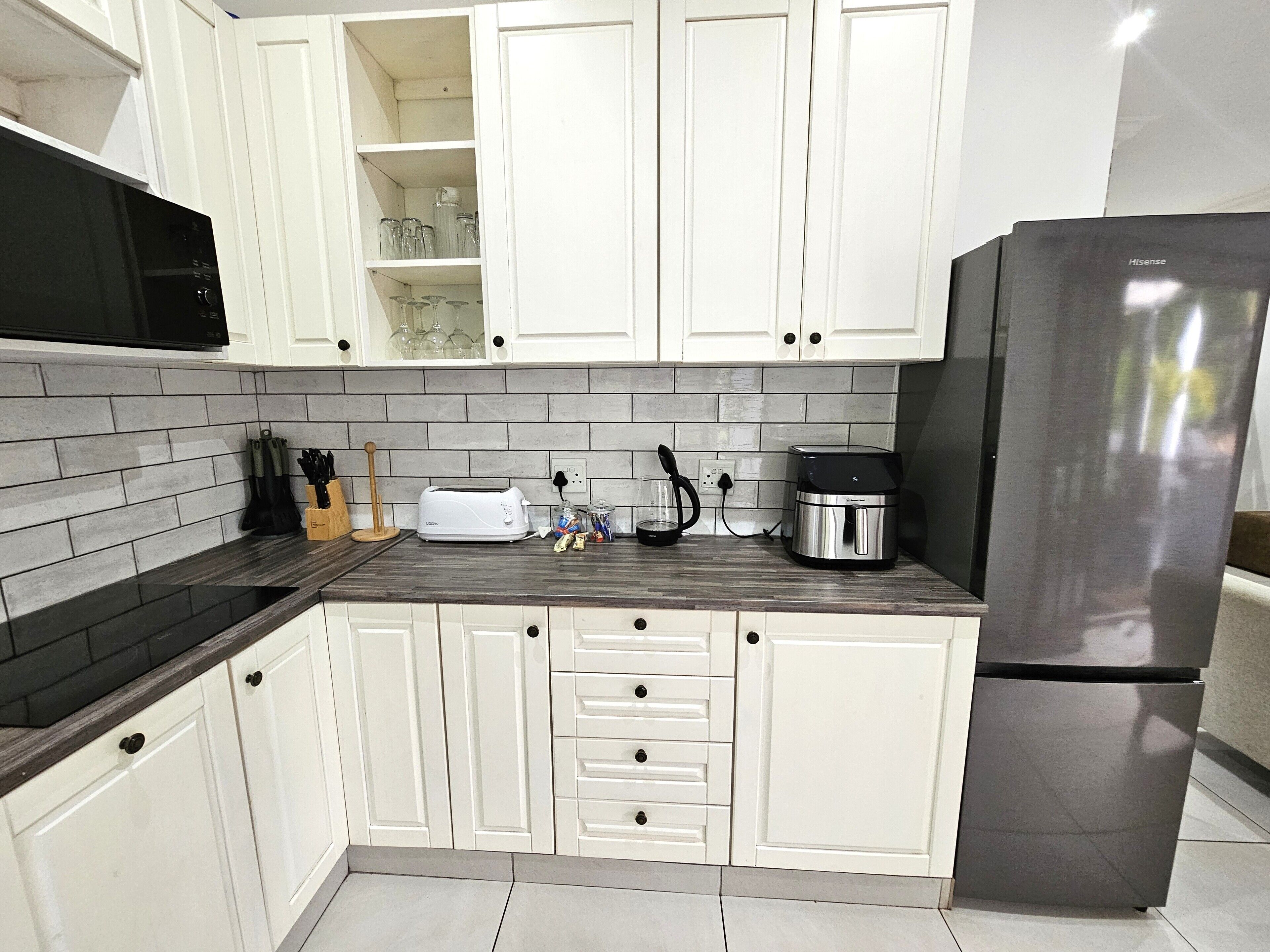 A kitchen with white cabinets, a stainless steel refrigerator, a toaster, and a coffee maker on the counter.