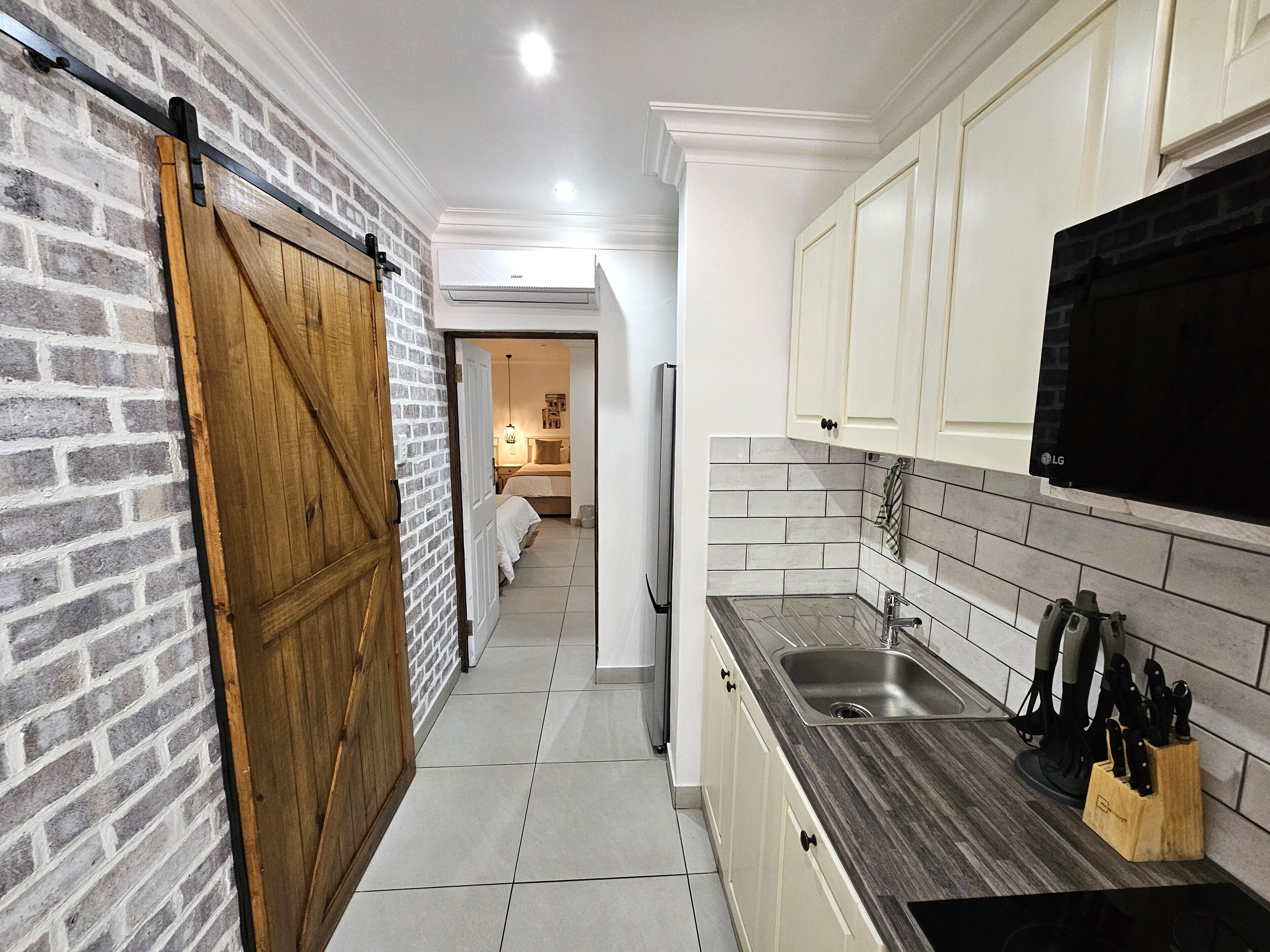 Una cucina stretta con una porta a scrigno, forno integrato e lavello con portacoltelli.