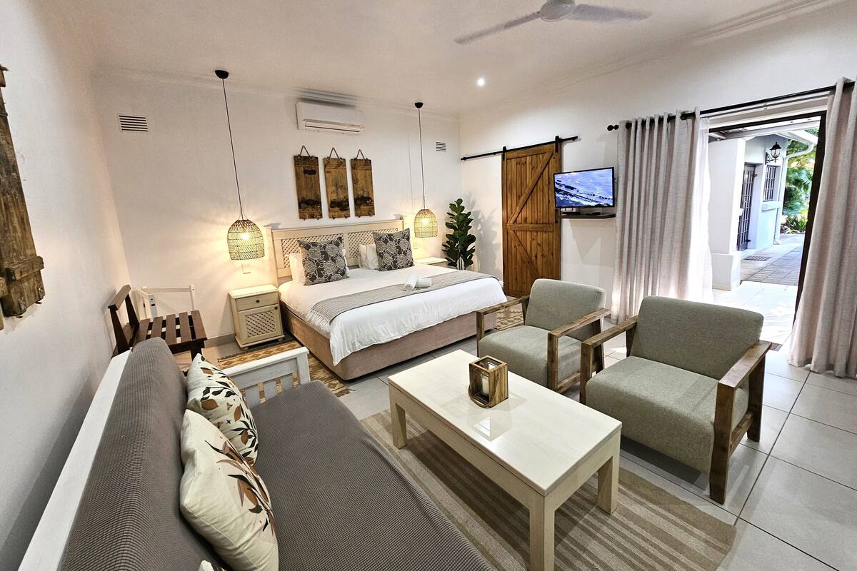 A modern bedroom with a bed, a sofa, a coffee table, and a TV.