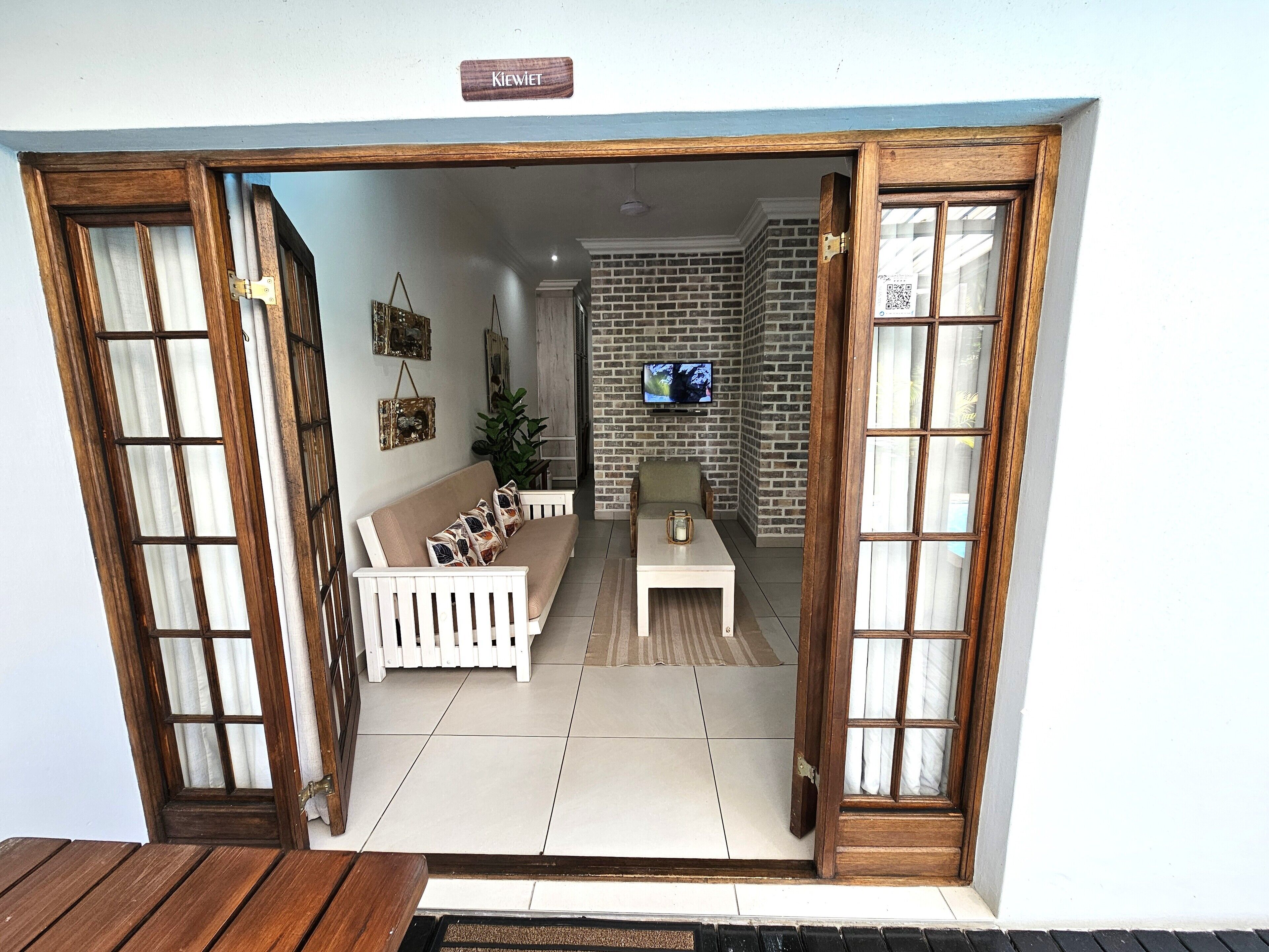 Una habitación con sofá, una mesita y televisor montado en la pared.