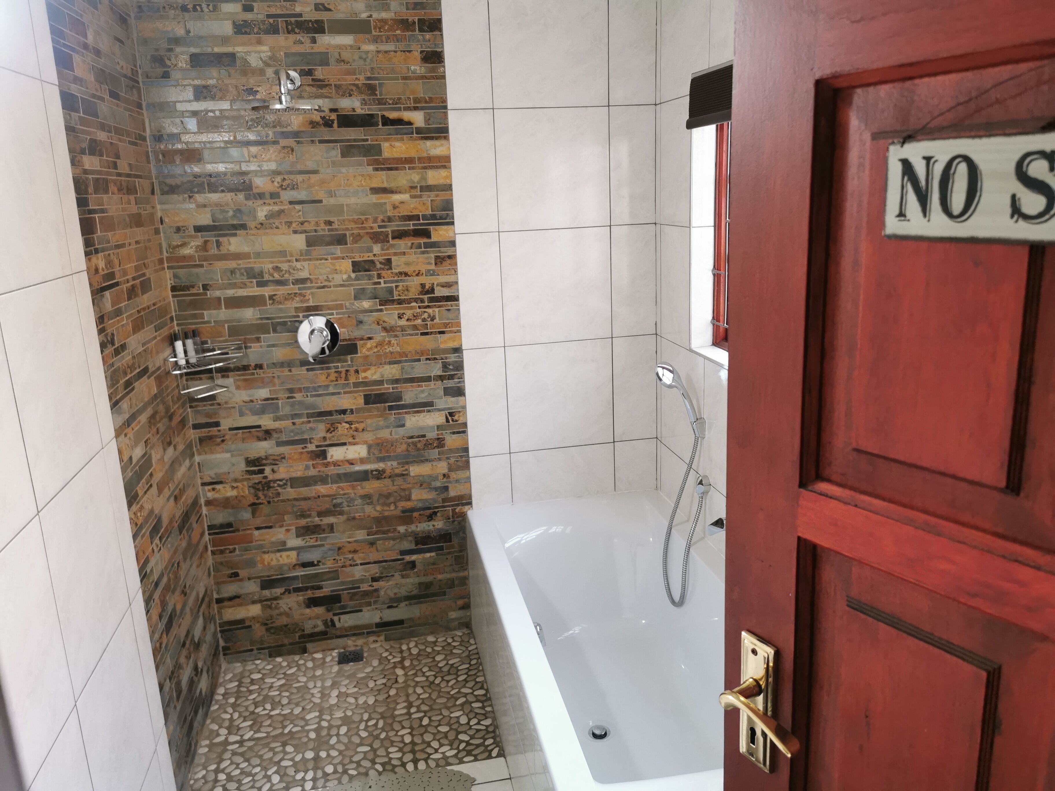 A bathroom with a shower, tiled walls, and a door with a sign.