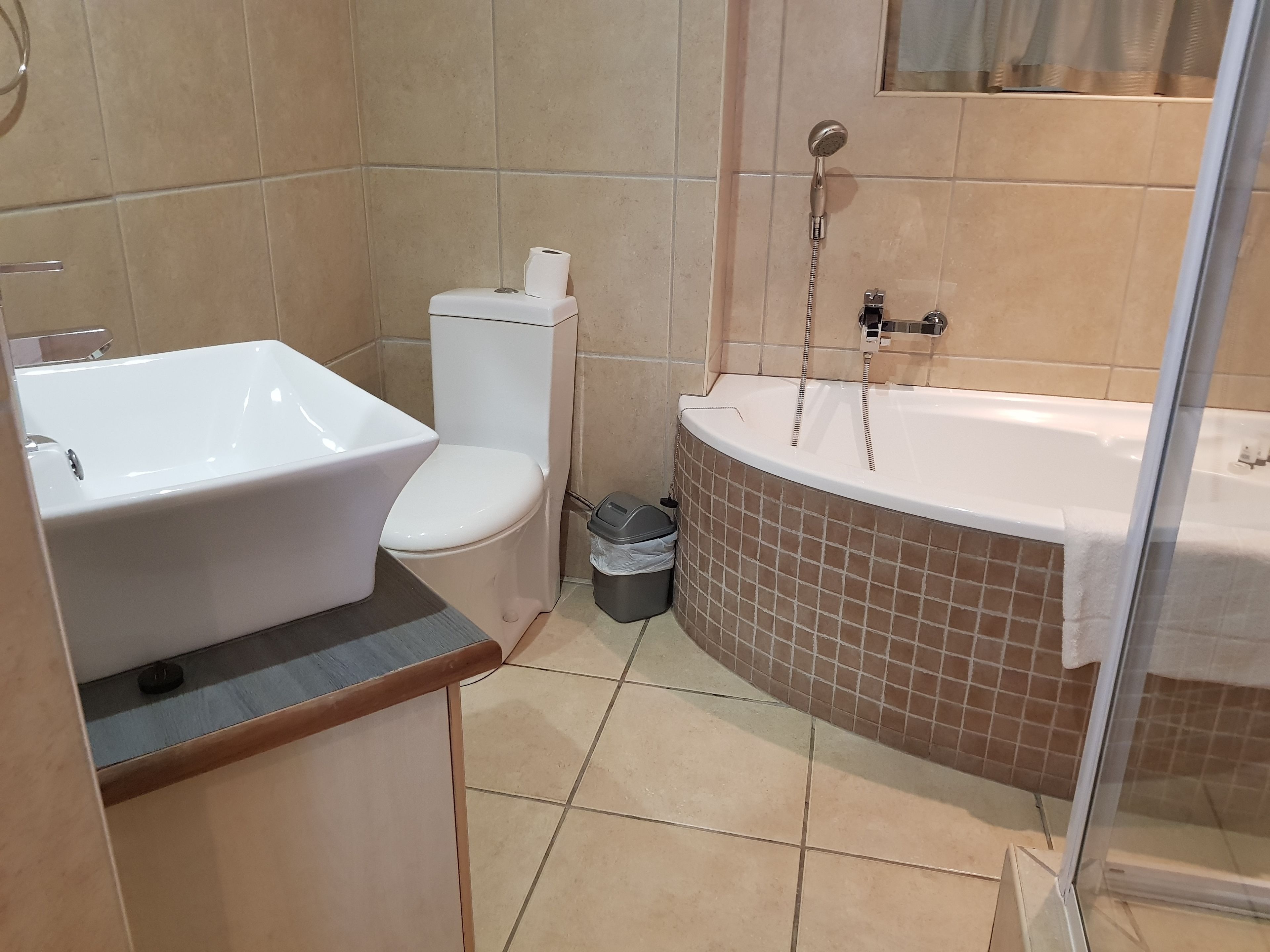 Een badkamer met een wit wastafel, toilet en bad.