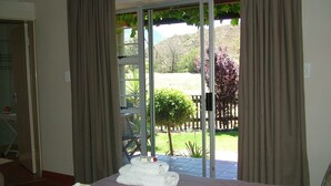 A hotel room with a bed, a bathroom, and a sliding glass door leading to a garden. - Damas (Worcester)
