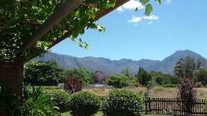 A garden with a wooden pergola, a well-maintained lawn, and a mountain backdrop. - Damas (Worcester)