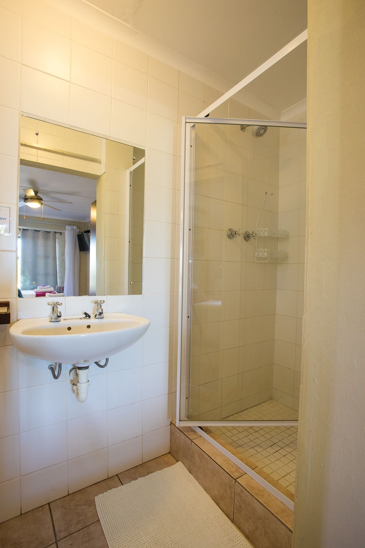 A bathroom with a white sink, a mirror, and a glass-enclosed shower.